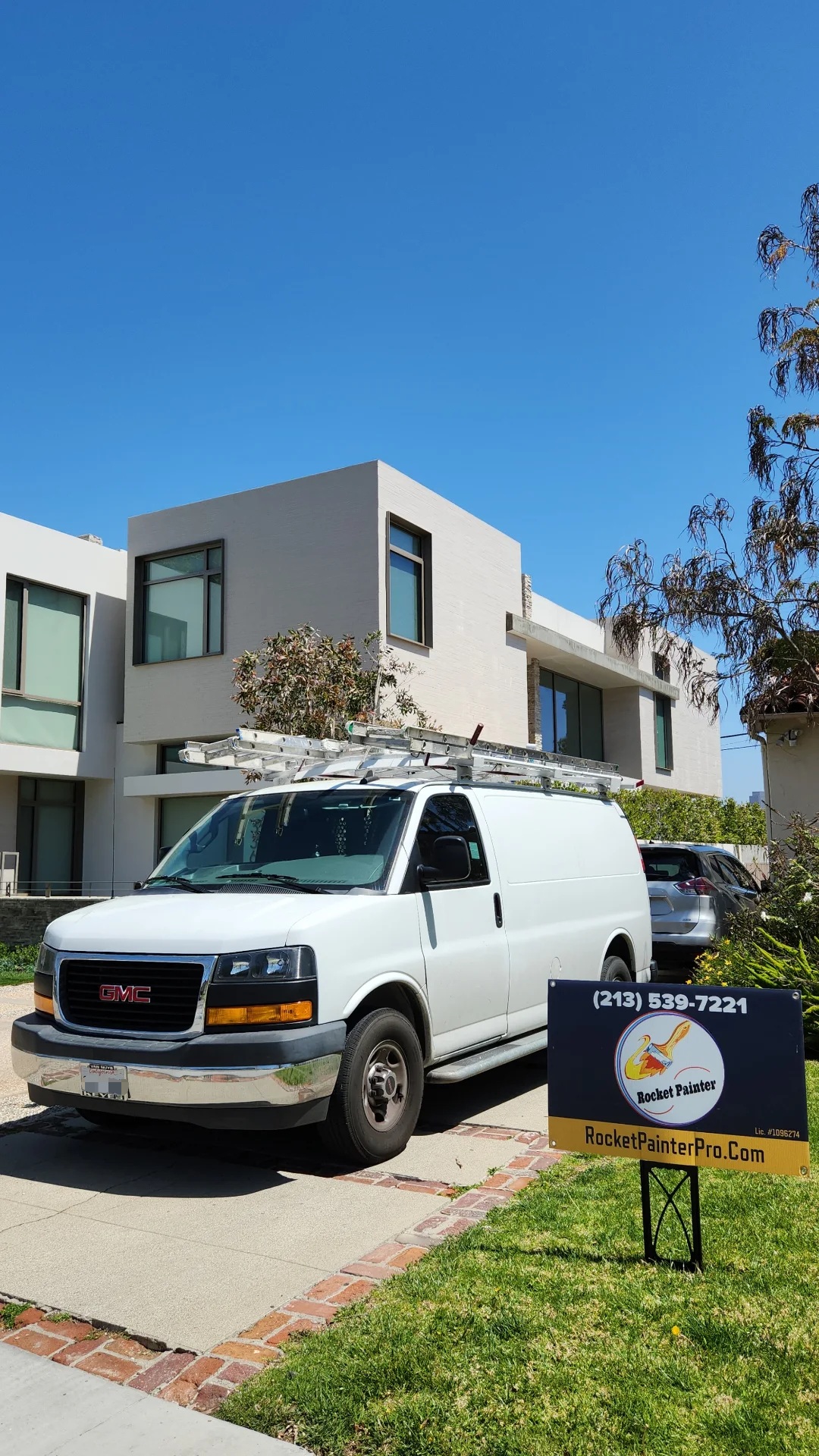 Modern minimalist  house with a white smooth stucco. White painter's van in the front.